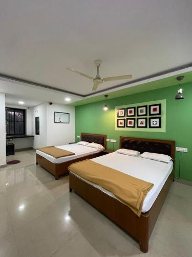 two beds in a room with a green wall at Hotel sai advika in Guirim