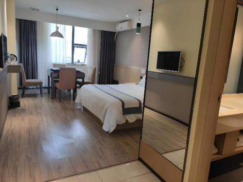 Habitación de hotel con cama, mesa y espejo en City Comfort Inn Jiangxia Wuchang University of Technology, en Wuhan