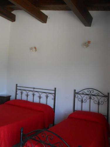 two beds in a room with red sheets at Agriturismo La Casetta in Tossicia