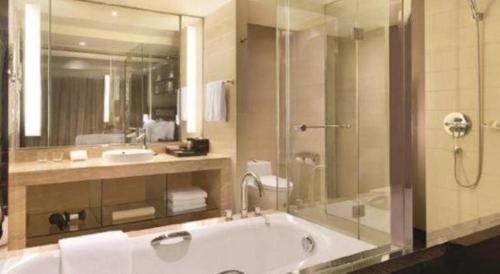 une salle de bain avec une baignoire, une douche et un lavabo dans l'établissement Ramada Plaza by Wyndham Lianyungang, à Haizhou