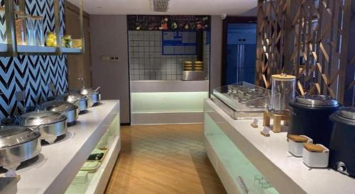 une cuisine avec de nombreux casseroles et poêles sur un comptoir dans l'établissement Borrman Hotel Zhanjiang Wuchuan Jinsha Plaza, à Xindi