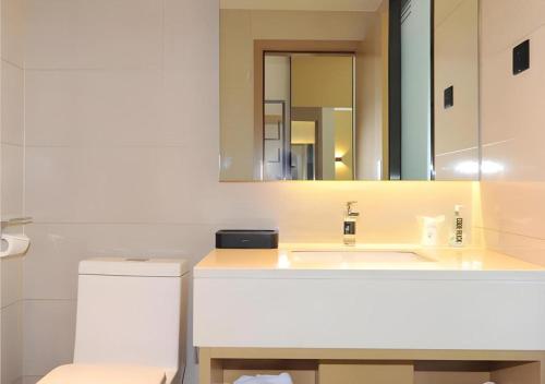 une salle de bain avec un lavabo et un miroir dans l'établissement City Comfort Inn Chengdu Transportation Technical College Traditional Chinese Medicine, à Chengdu