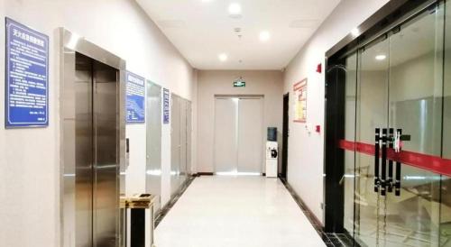 un couloir d'un immeuble avec un ascenseur et une porte dans l'établissement Pai Hotel Guang'an Railway North Station, à Guang'an