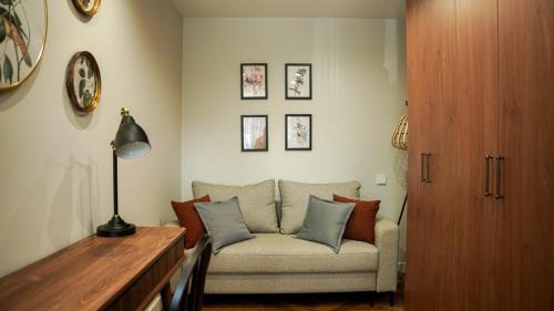 a living room with a couch and some pictures on the wall at Апарт-отель ЗОЛОТОЙ КВАДРАТ premium in Almaty