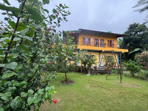 a yellow house with a yard with a tree at Baloo's Family homestay in Pokhara