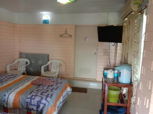 a bedroom with a bed and two chairs and a television at พักดีโฮม วิวหมอก เขาค้อ in Khao Kho