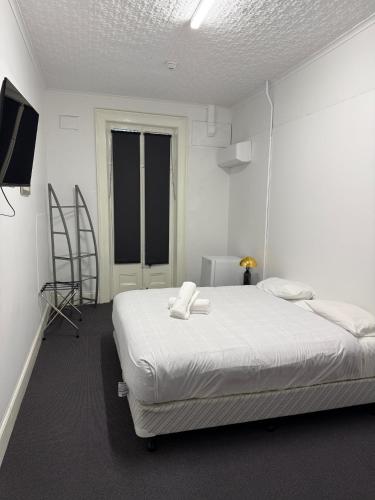 a white bedroom with a bed and a television at Eatons Hotel in Muswellbrook