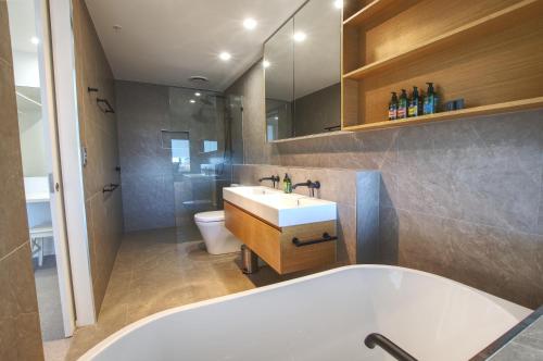 a bathroom with a tub and a sink and a toilet at Rise Maroochydore in Maroochydore