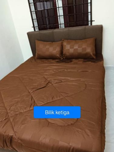 a bed with a brown comforter and two pillows at CD Homestay 