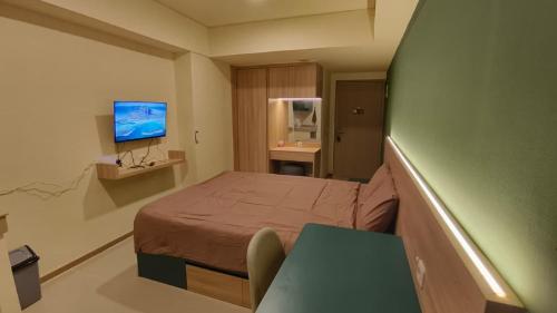 ein kleines Zimmer mit einem Bett und einem Fernseher in der Unterkunft Apartemen Meikarta by WhiteBox in Tegaldanas