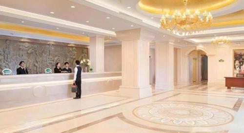 Un homme debout dans un hall avec un groupe de personnes dans l'établissement Vienna Hotel Guangxi Beiliu Passenger Station, à Beiliu