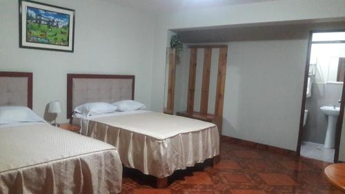 a hotel room with two beds and a sink at Antares Inn in Lima