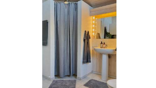 une salle de bain avec un lavabo et un rideau de douche dans l'établissement Vakantiehuis Vlakbij Zee En Gezellig Sæby, à Sæby
