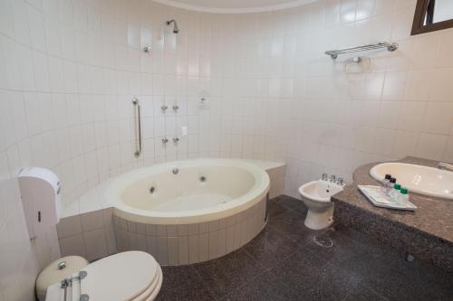 a bathroom with a tub and a toilet and a sink at Cardum Hotel in Sorocaba