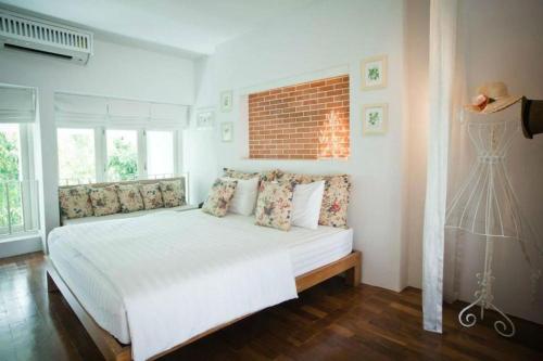 a bedroom with a white bed and a brick wall at Baan Hmon-Oon in Chiang Mai