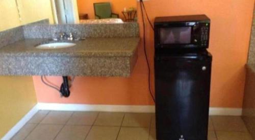 a bathroom with a counter with a sink and a microwave at Coast Motel in Signal Hill