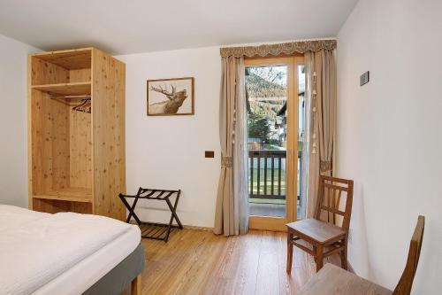 um quarto com uma cama e uma porta para uma varanda em Olympic Chalet 11 em Bormio