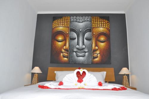 Una cama con dos grandes estatuas de cabezas. en Bubu Inn, en Ubud