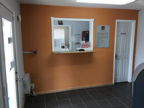 a hallway with an orange wall with a window at Cajun Country Inn in Gonzales
