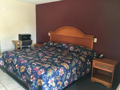 a hotel room with a bed with a floral bedspread at Cajun Country Inn in Gonzales