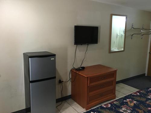 a room with a refrigerator and a dresser and a television at Cajun Country Inn in Gonzales