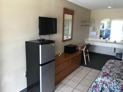a room with a refrigerator and a bed and a television at Cajun Country Inn in Gonzales