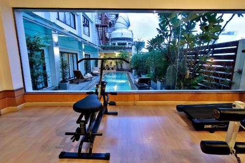 a fitness room with a gym with a swimming pool at Bossotel Bangkok in Bangkok