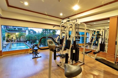 a gym with two tread machines and a swimming pool at Bossotel Bangkok in Bangkok