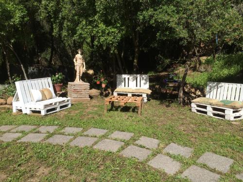 a group of three chairs and a statue in a yard at Cabañas Rahue in Vilches