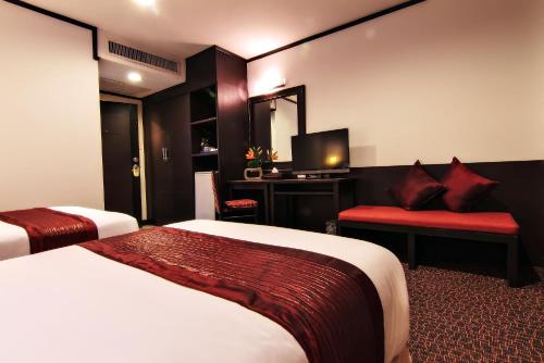 a hotel room with two beds and a television at Bossotel Bangkok in Bangkok