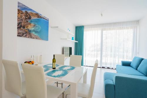 een witte eetkamer met een tafel en een blauwe bank bij Apartment SuperSeaView in Sutomore