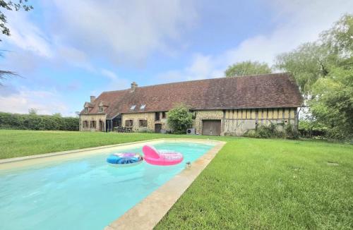 dois barcos insufláveis numa piscina em frente a uma casa em Longère de charme, calme & piscine em Armentières-sur-Avre