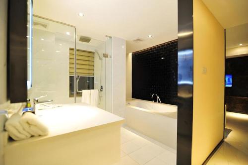 une salle de bain avec un lavabo, une baignoire et un miroir dans l'établissement GreenTree Alliance Hotel Guiyang Huaguo Community Central Business Zone, à Guiyang