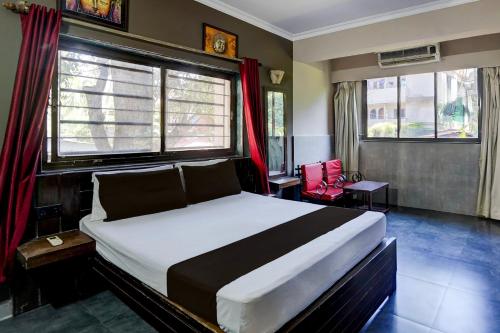 a bedroom with a large bed and two windows at Hotel O Calangute-Baga Crossway Formerly Rustic Village in Calangute