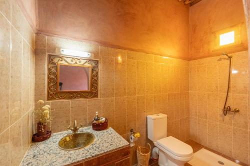 a bathroom with a sink and a toilet and a mirror at Riad Imuhar Prestige - Mhamid Desert Retreat in Mhamid