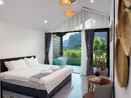 a bedroom with a bed and a large window at Mini Vangvieng Resort in Vang Vieng