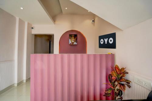 プネにあるHotel O Elite Stayの壁に時計が掛かっている部屋のピンクの仕切り