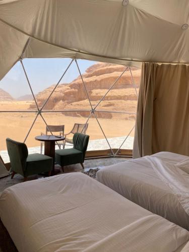 a tent with two beds and a table and chairs at WADI RUM TARA lUXURY CAMP in Wadi Rum