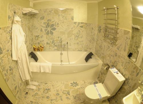 a bathroom with a bath tub and a toilet at Hotel Mir in Rivne