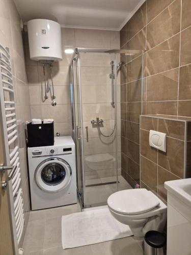 a bathroom with a shower and a washing machine at Hari Apartmani Oaza in Tuzla