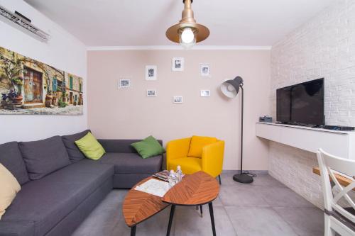 a living room with a gray couch and a yellow chair at HaBaitBe Matityahu By Domus in Beer Sheva
