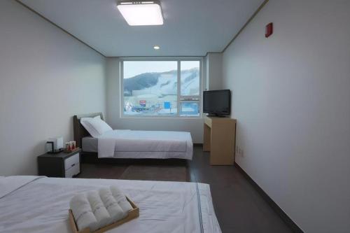 a hotel room with two beds and a window at Pyeongchang the white view in Pyeongchang 