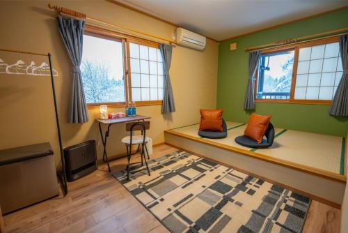 a room with a bed with a desk and windows at urara house guesthouse in Wada