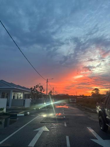 Un coche circulando por una calle con una puesta de sol. en NHI Home Paka, en Paka