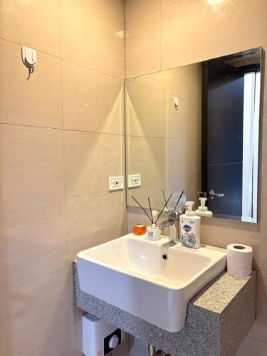 a bathroom with a white sink and a mirror at 2BR Sunset View Deluxe Suite in Manila