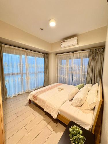 a bedroom with a large bed and large windows at 2BR Sunset View Deluxe Suite in Manila