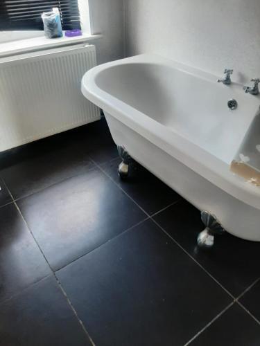 a white bath tub sitting in a bathroom at Lodge near Merry Hill Shopping centre in Delph