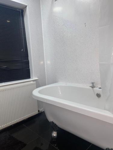 a white bath tub in a bathroom with a window at Lodge near Merry Hill Shopping centre in Delph