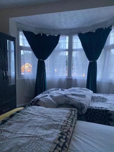 a bedroom with two beds with blue curtains and windows at Lodge near Merry Hill Shopping centre in Delph