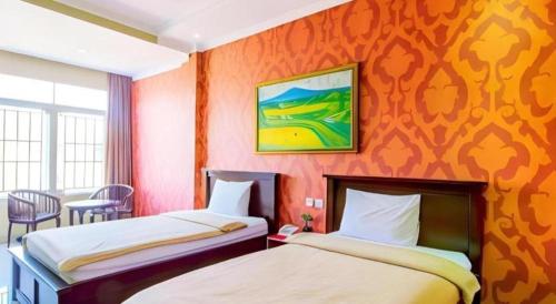 チウィデイにあるAlbis Hotelのオレンジ色の壁の部屋にベッドが2つある